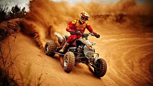 ATV driving through a desert dune setting.